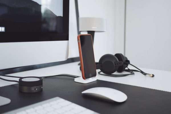 black iPhone charged on table near black headphones